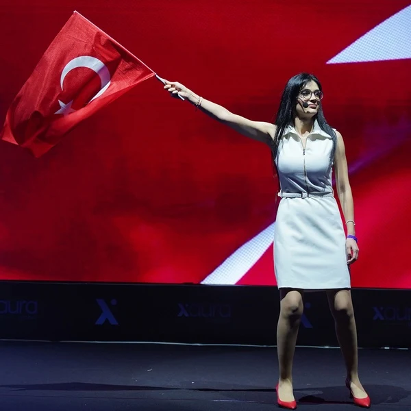 Xaura Global etkinliğinde elinde bayraklarla kollarını açan kadın katılımcı